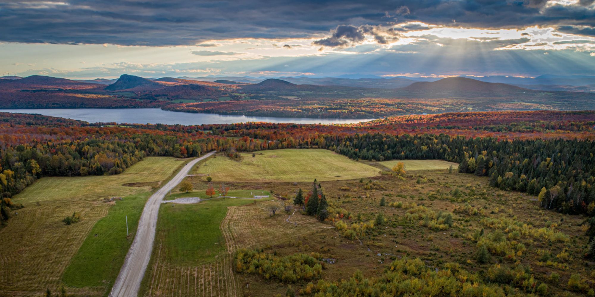 An aerial shot over Sentinel Rock State Park shows Lake Willoughby in the distance amidst a sea of fall colors